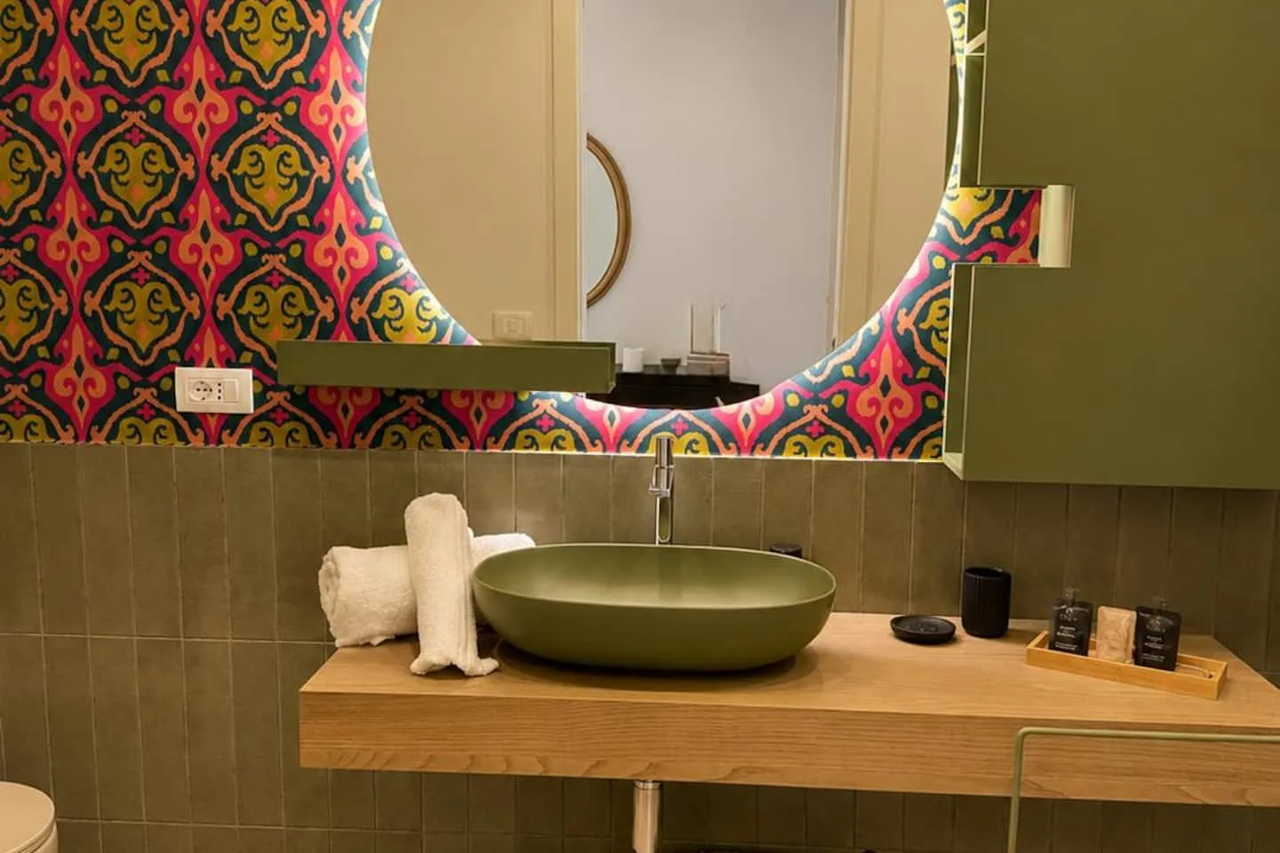 Lo specchio retroilluminato e la mensola in legno con il lavabo verde