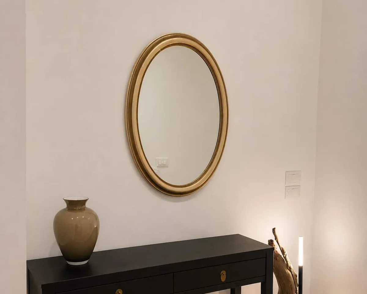 La consolle nera con il vaso e lo specchio ovale dorato