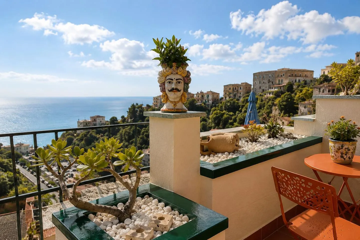 Il terrazzo con la testa di moro, i tavolini arancioni e il mare sullo sfondo