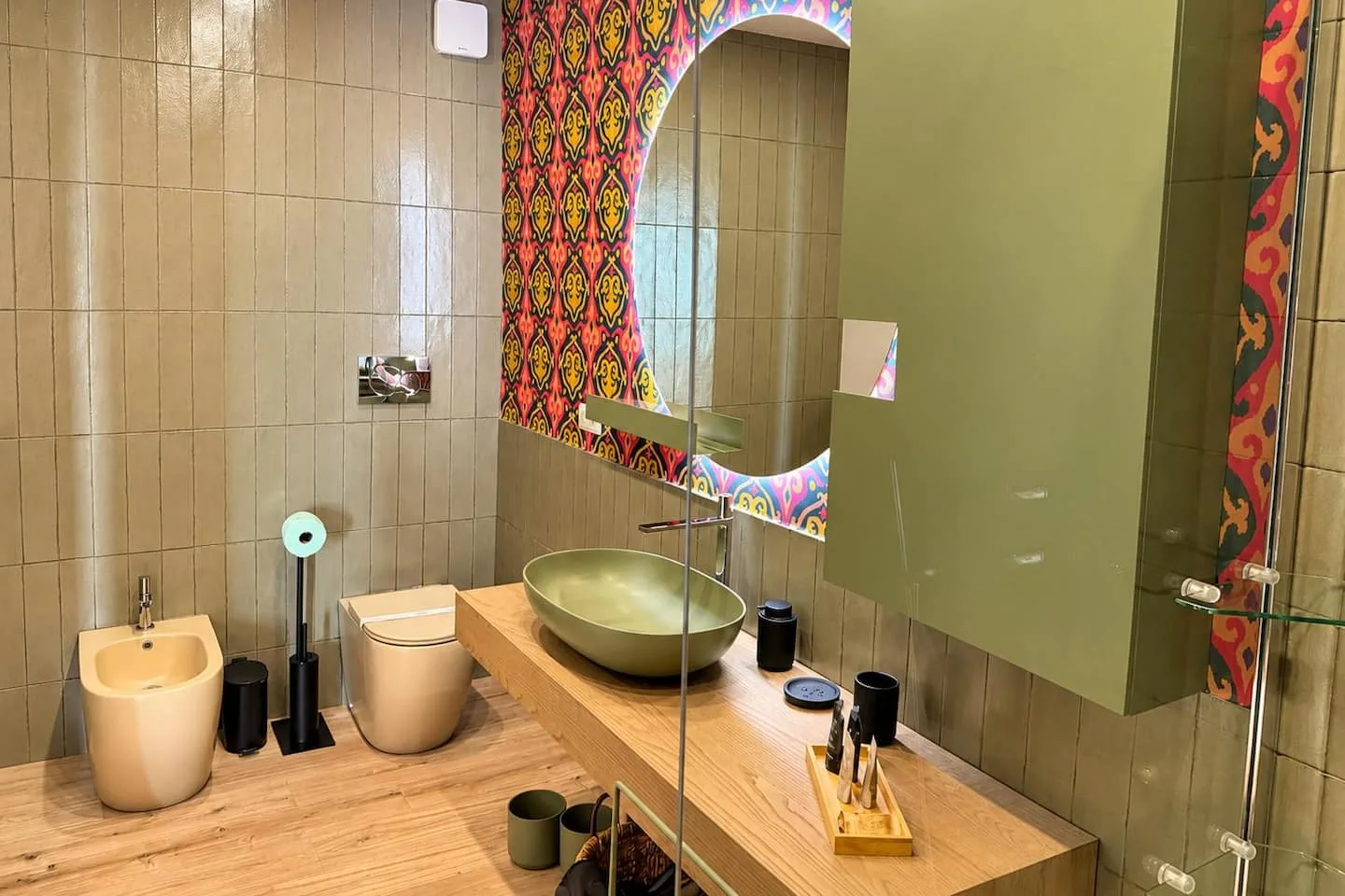 Il bagno: lavabo verde, specchio tondo e parete in maiolica