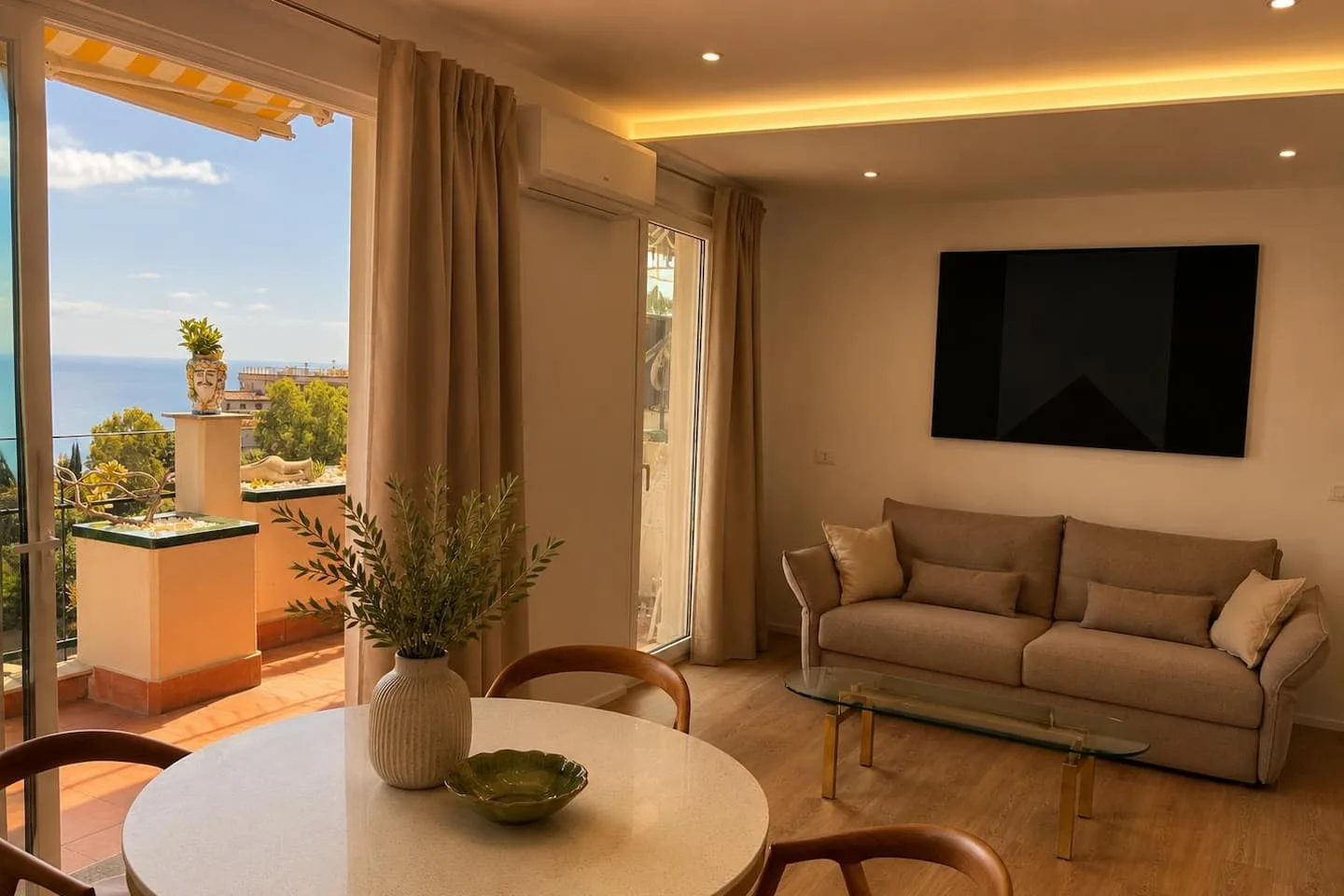 Il soggiorno, con il tavolo rotondo e la porta finestra aperta sul terrazzo